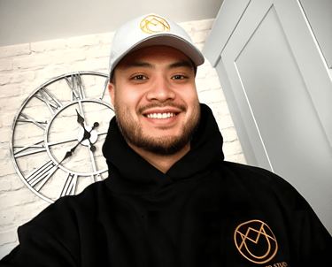 Yau, founder of YAU Barber Studio, smiling in branded hoodie and cap with studio logo, representing professionalism.