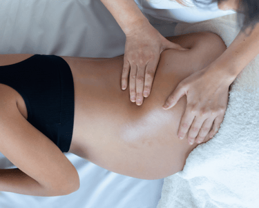 pregnant woman being massaged by massage therapists 