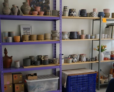 a display room with a couch and shelves with colorful handmade pottery