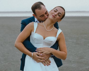 un marié qui embrasse sa femme dans le cou sur la plage