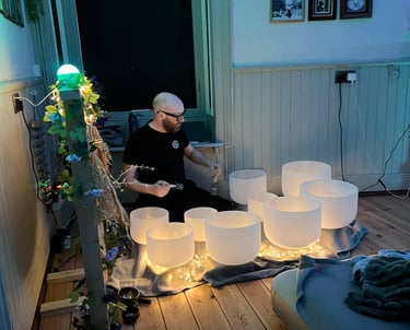 a man playing crystal bowls at night with fairy lights all around