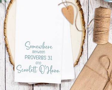 Kitchen towel printed with the saying "Somewhere between Provers 31 and Scarlett O'Hara" for Christian mom woman gift