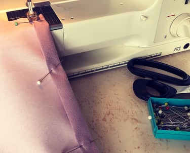 a piece of pink faux suede pinned on a sewing machine ready to be made into a cushion back