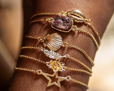 o braço de uma mulher com pulseiras pratas e douradas.