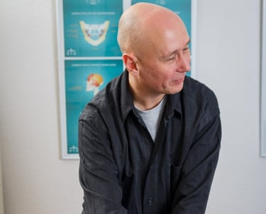a man in a black shirt and jeans sitting on a table