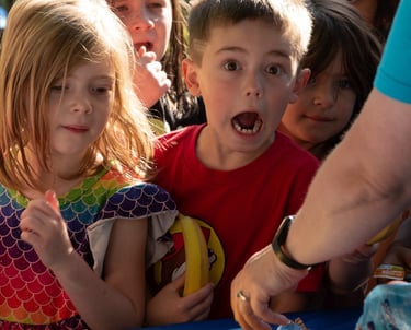 A group of children at a breakfast station getting bananas!