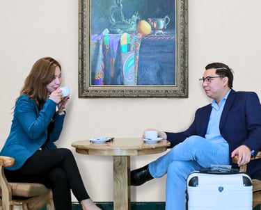 a businessman and woman sitting at a table with a suitcase
