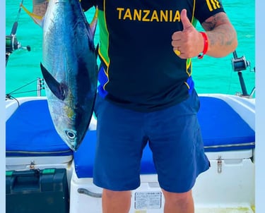 Happy tourist in Zanzibar proudly holding a big tropical fish after an exciting fishing trip on the Indian Ocean