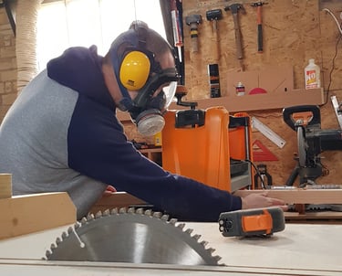 a man in a respirator mask and ear defenders in a workshop