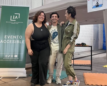 Los integrantes de IA sonríen frente a carpa rotulada “Espacio de calma” en un evento accesible.