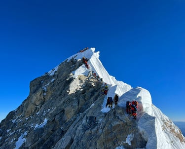 Climbers on snowy peak – Mountaineers ascending a snow-covered mountain ridge under a clear blue sky