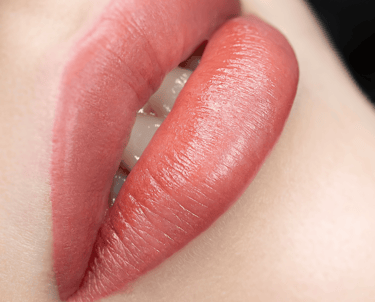 Close-up of beautiful lip blush tattoo on a client's lips, showing a soft pink tint