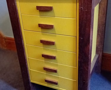 Bright yellow metal filing drawers with wooden handles with a wooden frame, legs and top