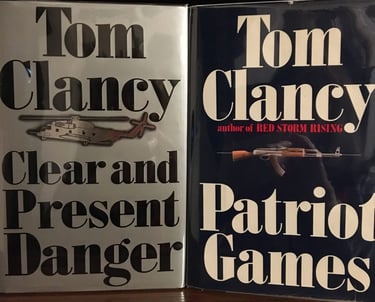 two Tom Clancy books with guns and a helicopter