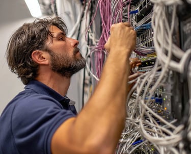 a man in a blue shirt is looking at a bunch of wires