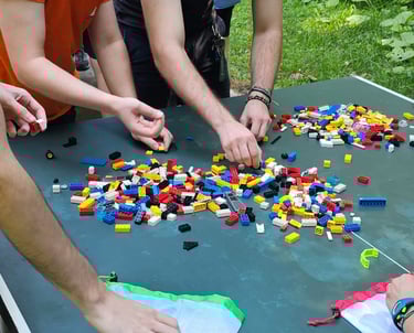 a group of people standing around a table with legos
