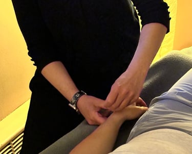 Acupuncturist inserting needle into patient’s wrist on acupuncture table. 
