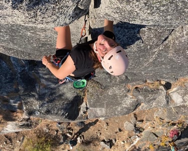 A smiling person climbing a rock face