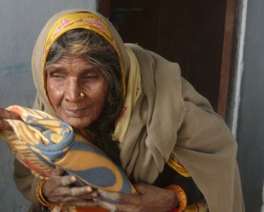 an old woman in a yellow shawl holding a blanket