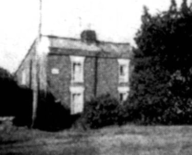 An old photograph of a pair of red brick cottages
