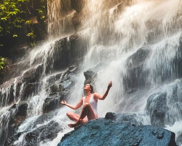 Brava Braun doing yoga on a rock in front of a waterfall