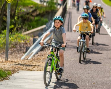 Photo of a bunch of kids riding on a sidewalk over a bridge