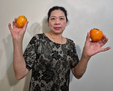 a woman holding two persimmons in her hands