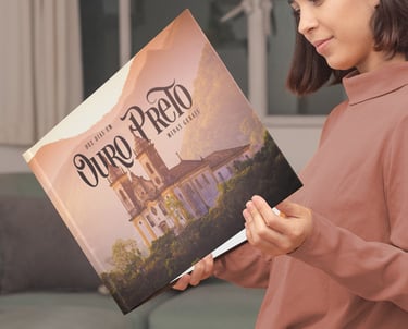 Mulher sorrindo ao folhear álbum de viagem personalizado de Ouro Preto na sala de estar.