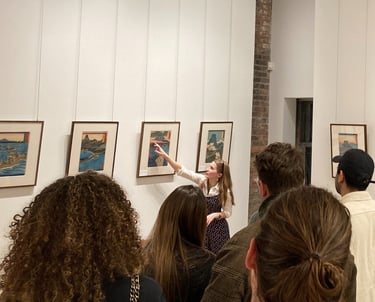 Madison pointing at a print while leading an exhibition tour for a large group