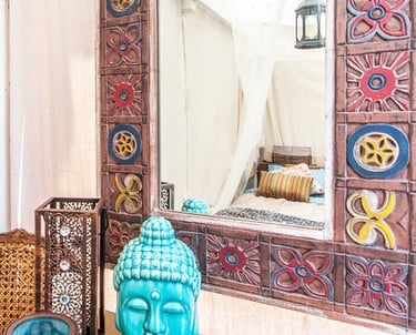 a buddha statue sitting on a table with a mirror
