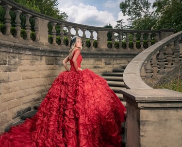 a quinceañera in a red dress standing on a staircase