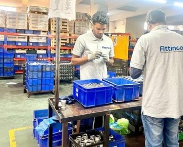 Factory workers at Fittinco inspecting high-quality hydraulic hose fittings in a manufacturing warehouse.
