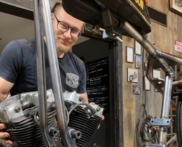 a man holding an engine behind a motorcycle frame.