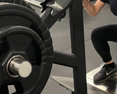 Donna che esegue squat su una macchina per leg press nella palestra Move 2 Grow a Milano, circondata da attrezzature per l'al