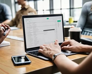 Vista em close de profissional redigindo e-mail em um notebook sobre mesa de madeira