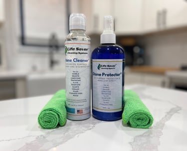 Life Saver Stone Cleaner and Stone Protector bottles with green microfiber cloths on a marble countertop.