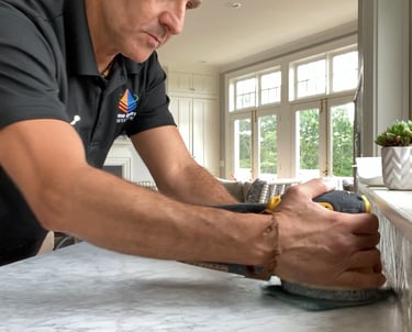 Professional contractor using a power sander for marble countertop restoration and honing