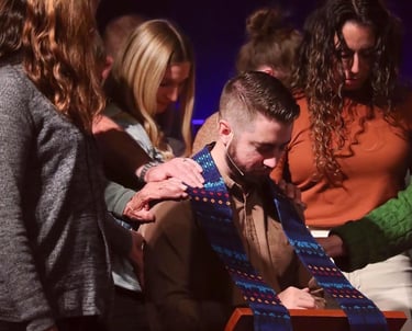 Cole bowed in prayer during what appears to be an ordination or commissioning ceremony.