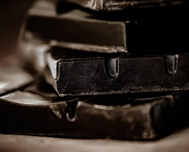 Close-up of stacked dark chocolate bars with a moody, cinematic aesthetic and soft lighting.