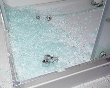 Broken safety glass scattered over a shower tray and bathroom floor – shows a shattered shower door