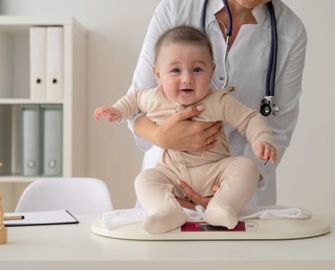 Un pediatra pesando a un bebé sonriente en una báscula digital durante un chequeo de bienestar.