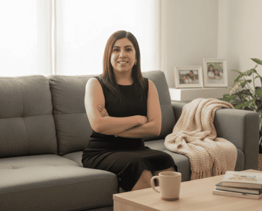 Dra Isis Alvarado Pediatra con vestido negro sentada en un sofá gris en una oficina en casa moderna.