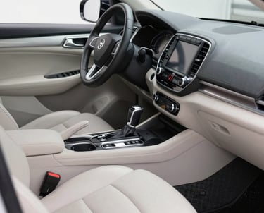 A professional cleaner wiping down the dashboard of a car inside a bright garage.
