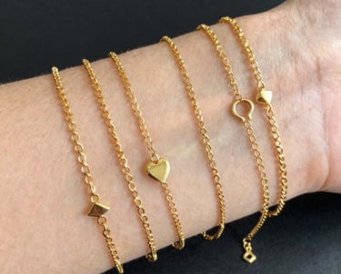 Close-up of delicate permanent bracelets and necklaces glowing softly on wrists and necks.