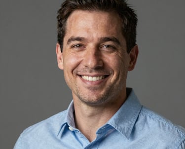 A professional headshot of a man named Daniel, smiling warmly and professionally, wearing a light blue shirt, North American / US style.