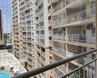A technician carefully installing a sturdy safety net on a high-rise balcony in Hebbal.