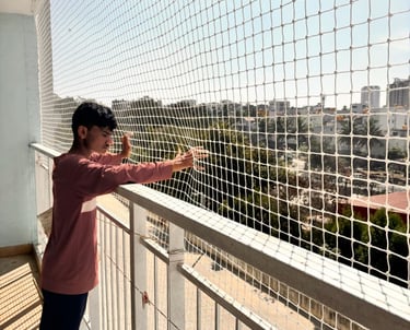 Technician from Sukumari Safety Nets carefully fixing netting around a window frame.