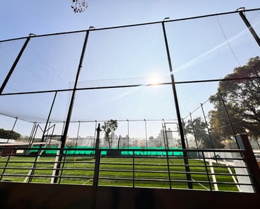 Technician fitting a sturdy sports net on a cricket practice cage under bright daylight.
