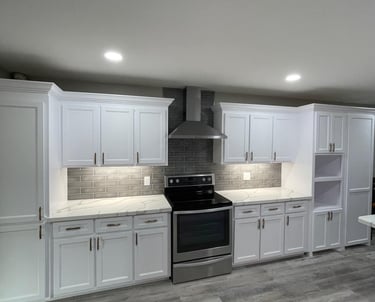 Modern white kitchen cabinets with marble countertops, grey subway tile backsplash, and stainless steel appliances.