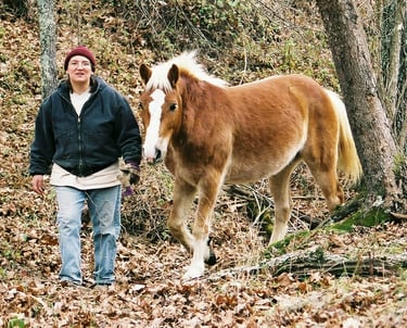 Leah Kyaio leading a pony in the woods without a lead